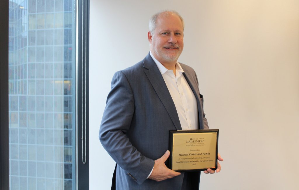 Michael posing with 2019 Outstanding Service Award certificate from Geriatric Centre Foundation