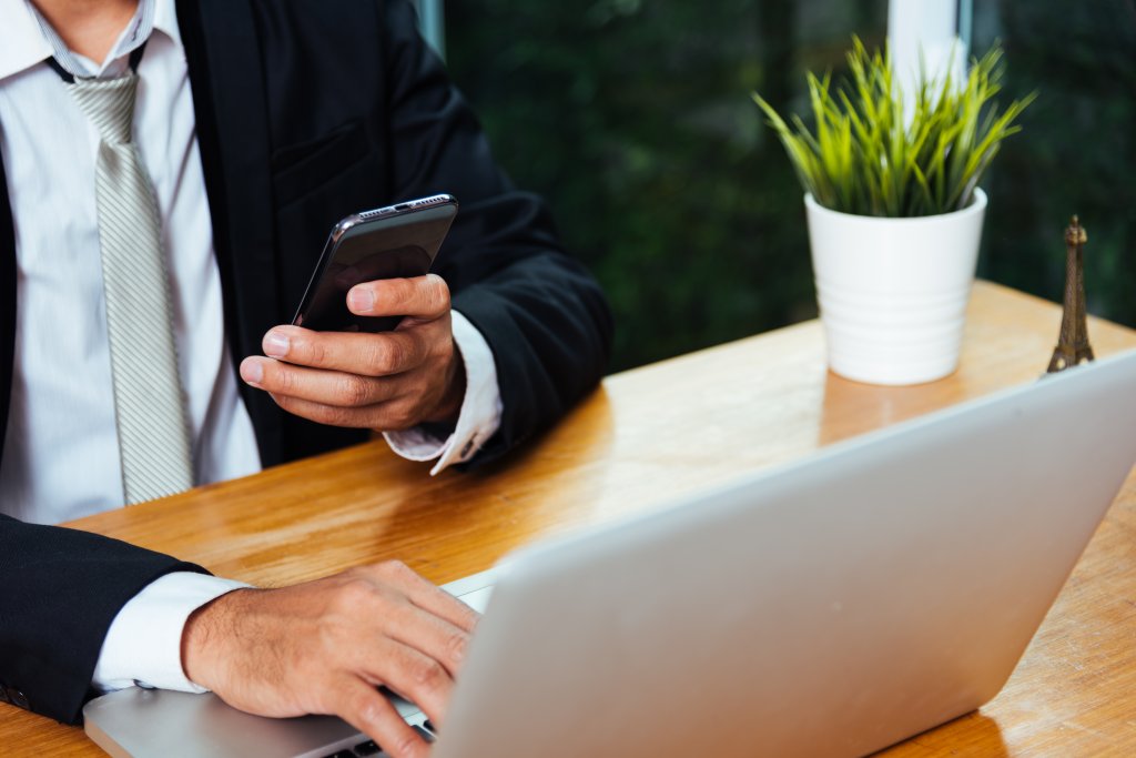 person checking business info on their phone and computer