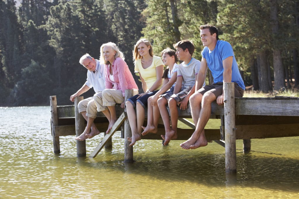 3 generational family seated by a lake 