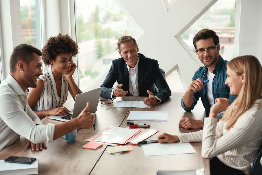 younger clients seated with their financial advisor at a table - talking and laughing 