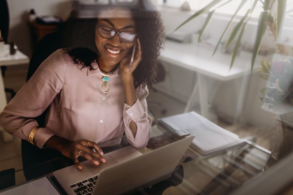 business person speaking on the phone and scrolling on their computer 