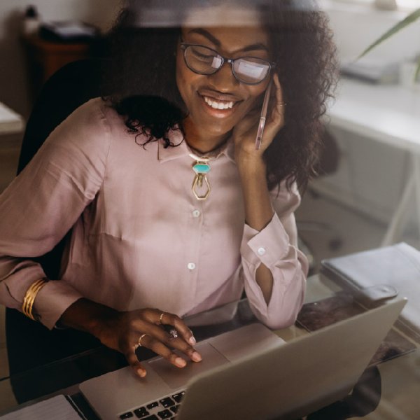 Person talking on the phone while looking browsing on her computer