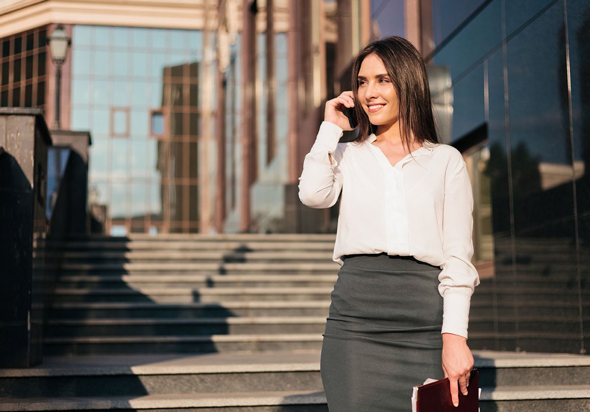 A smiling woman talking on the phone outside