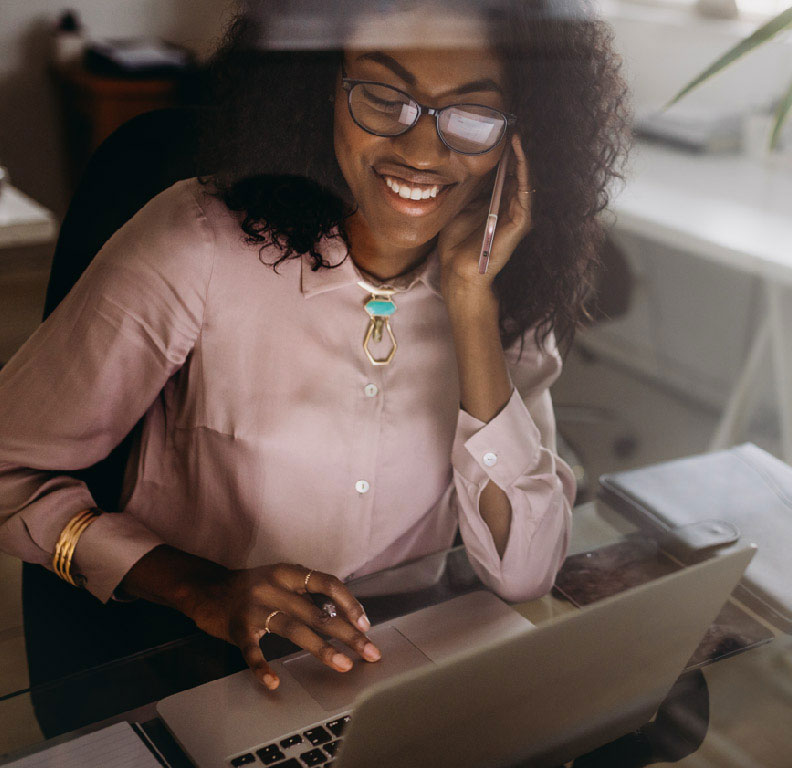 Person talking on the phone while looking browsing on her computer