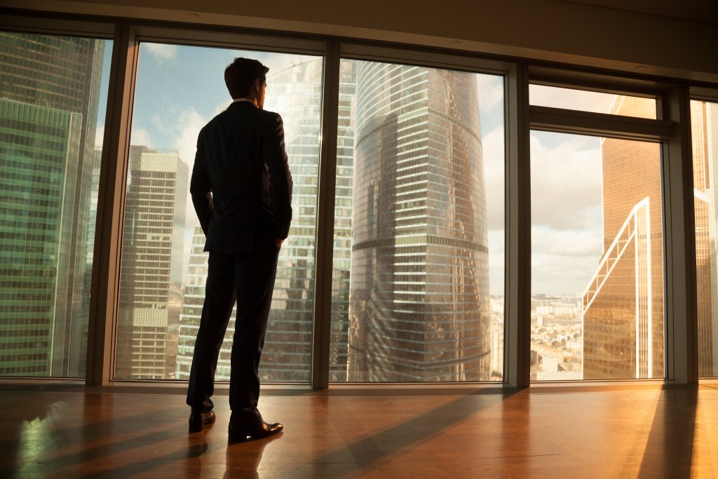 man staning by a window overlooking the city