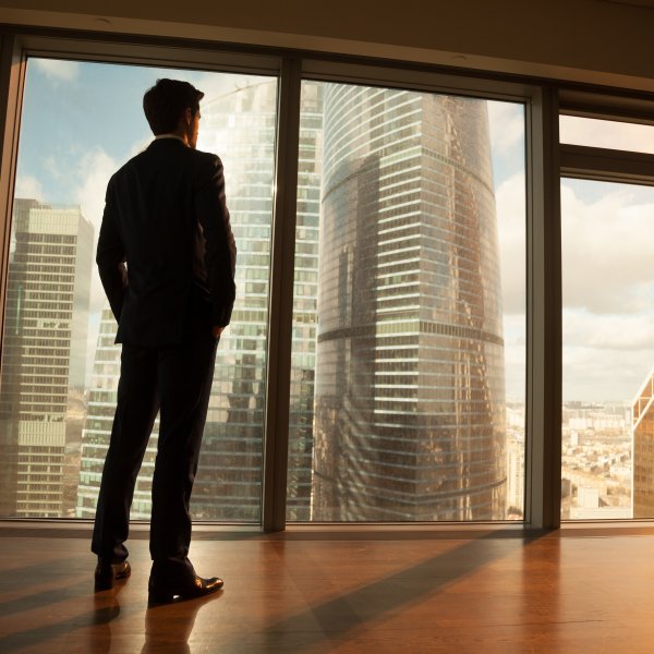 man staning by a window overlooking the city