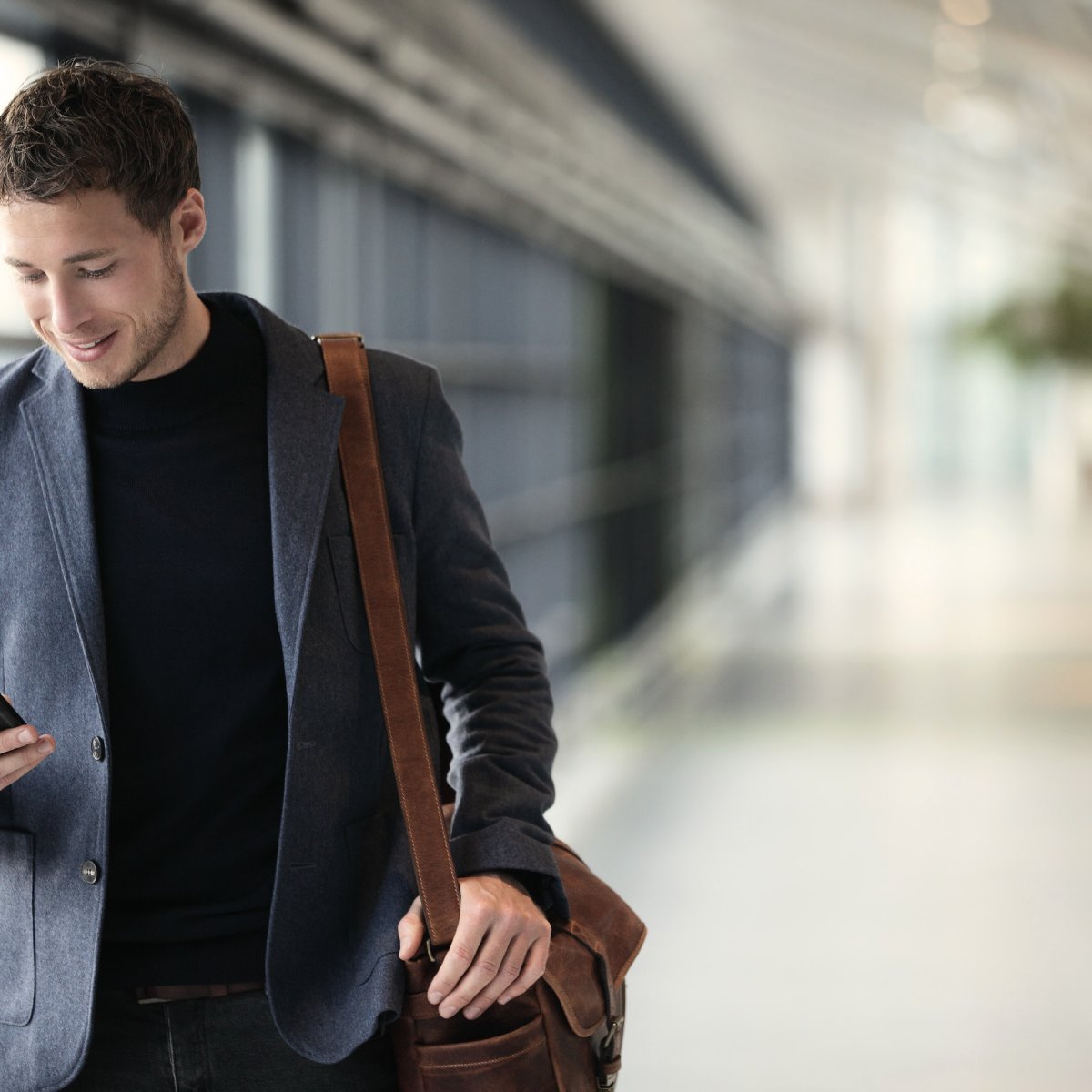 Man walking down hallway looking at his phone