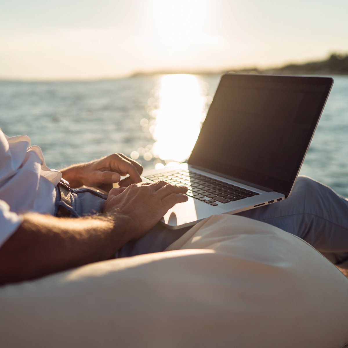 A person on their laptop while sitting on the beach