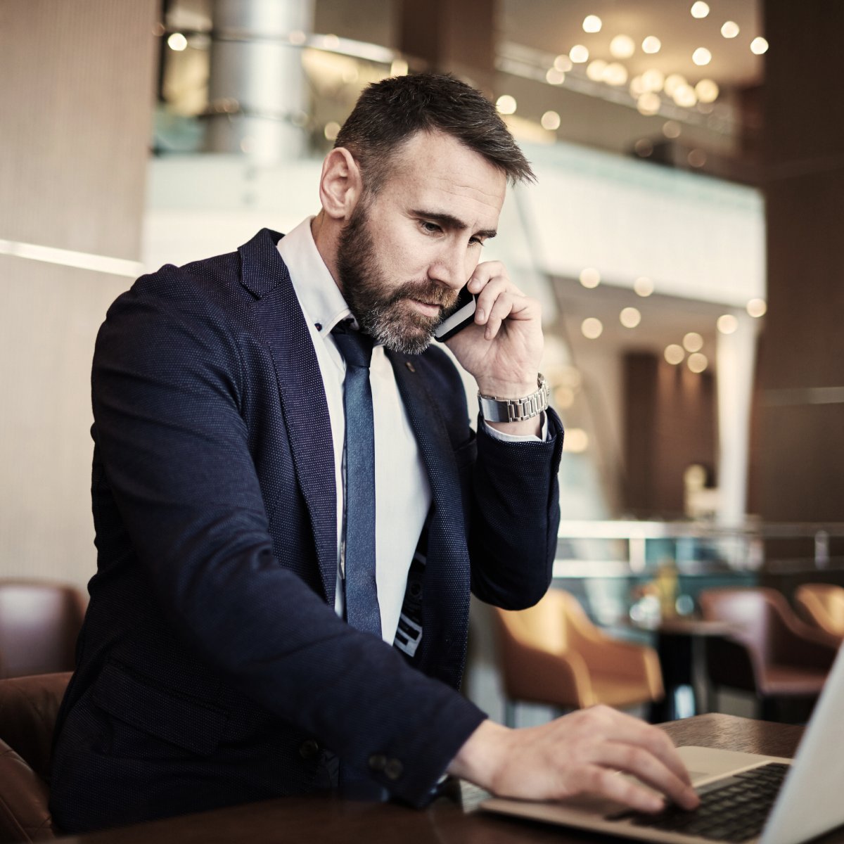 A man talking on the phone while working on a laptop